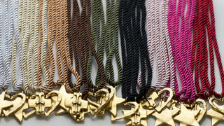 Collection of gold star-shaped pendants on various colored strings.