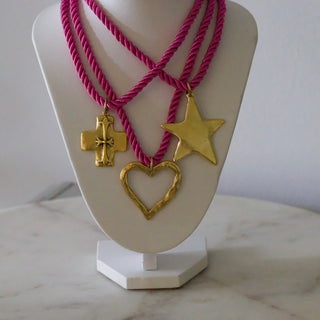 Necklace with gold pendants on a white stand against a marble surface