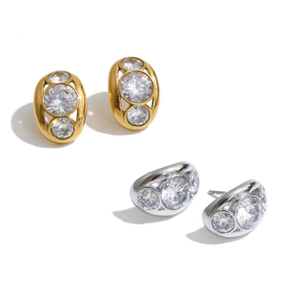 Two pairs of oval stud earrings on a white background: two gold-tone pairs with clear gemstones and one silver-tone pair.