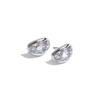 A pair of silver crescent-shaped stud earrings with three clear round-cut gemstones in each earring, displayed on a clean white background with soft shadows.