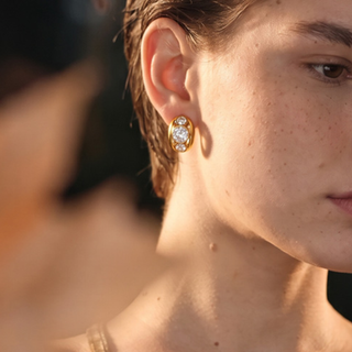 A woman with short hair wearing a pair of gold earrings. 
