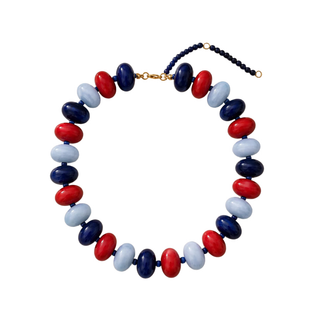 A beaded necklace with alternating red, navy blue, and light blue oval beads, featuring a gold clasp and extender chain on a plain white background.