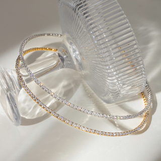 Glimmer Flex Choker in 18k gold plated and silver, rhinestone necklaces, displayed on a glass with sunlight