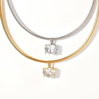Close-up of a crystal choker necklace with a clear solitaire pendant on a sleek snake chain in gold finish