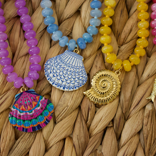 Colorful beaded necklaces with shell pendants on a woven surface
