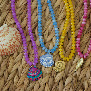 Colorful beaded necklaces with shell pendants on a woven surface