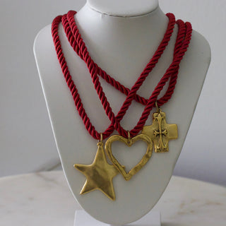 Red rope necklace with gold heart and star pendants on a mannequin bust.
