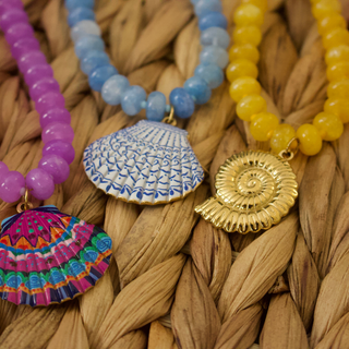 Colorful beaded necklaces with unique pendants on a woven surface