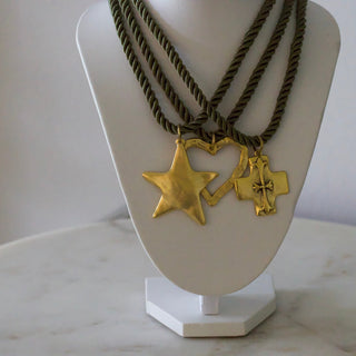 Gold necklace with star and heart pendants on a white stand.