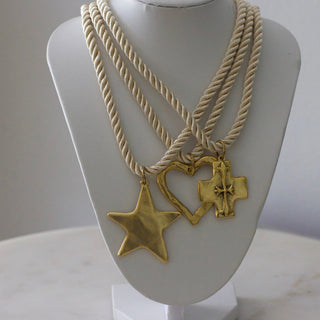 Gold necklace with star and cross pendants on a mannequin bust against a white background