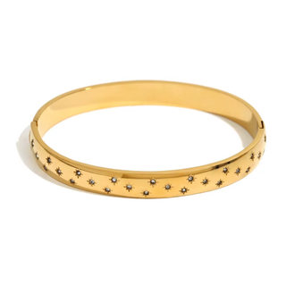 Gold bangle with star-shaped stones on a white background