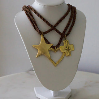 Necklace with gold star and cross pendants on a mannequin bust against a neutral background
