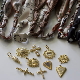 Collection of gold jewelry charms and hair ties on a light surface