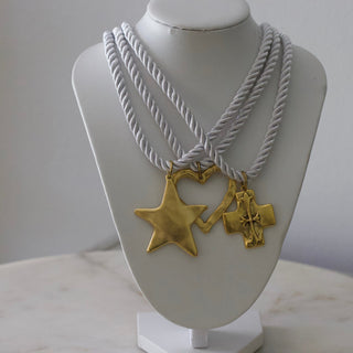 Necklace with gold star and cross pendants on a mannequin bust against a plain background