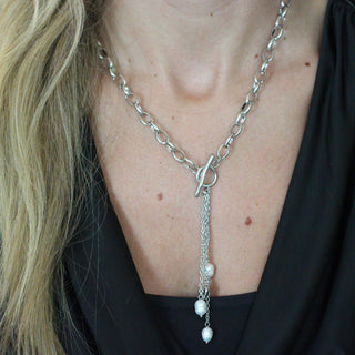 Close-up of a person wearing a silver chain necklace with a pendant.