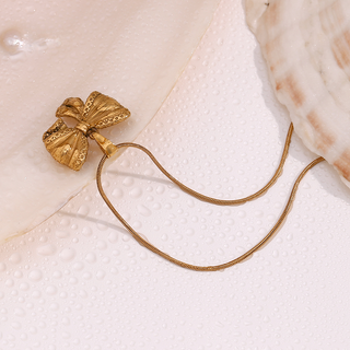 Belle Bow Necklace in gold-tone metal, featuring a textured bow pendant on a sleek, fine snake chain