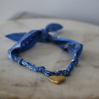 Blue Skies Heart Locket scarf necklace in blue patterned fabric, tied in a bow with a small gold heart pendant.