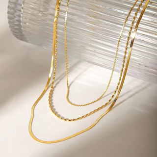 Golden Layers Triple Necklace with three gold-tone chains in varied fine link patterns and lengths, creating a layered look