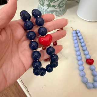 Hartley Heart Statement Necklace featuring oversized glossy navy blue acrylic beads with a bold red heart accent and gold-tone spacers