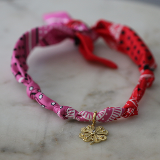 Lucky Charm Scarf Necklace with a twisted pink and red patterned fabric scarf and a gold four-leaf clover pendant