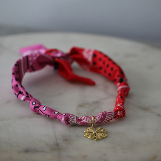 Lucky Charm Scarf Necklace in pink and red patterned fabric with a small gold four-leaf clover pendant