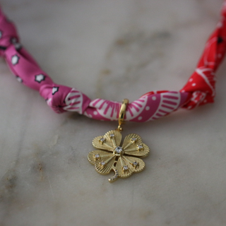Lucky Charm Scarf Necklace with a twisted pink and red patterned fabric band and gold-tone flower pendant with a clear center stone