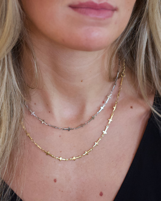 Mini Cross Necklace with delicate gold and silver-tone chains featuring small cross links, layered around the neck