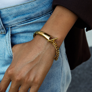 Monaco Curb Chain bangle bracelet in polished gold-tone metal, with a smooth cuff and dangling curb chain detail