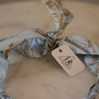 Skyline Heart Scarf Necklace with a pale blue and cream printed fabric scarf, gold-tone clasp and attached tag; no heart charm visible
