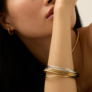Stacking Bangles Set with slim polished gold and silver metal bands, stacked in mixed tones around the wrist