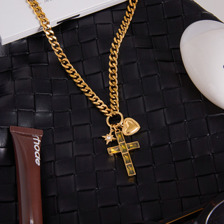 Trinity Necklace with a chunky gold-tone chain and cross, heart, and star charms, featuring dark green inlays